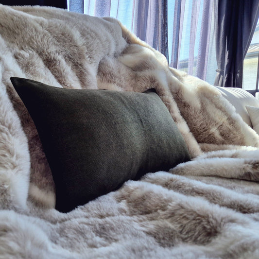 Amano Olive dark green cushion styled on a neutral sofa, showcasing the earthy green tones, wool blend fabric and sophisticated minimal aesthetic.