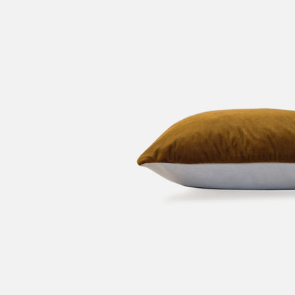 Side view of an amber velvet cushion cover with plush textured fabric.