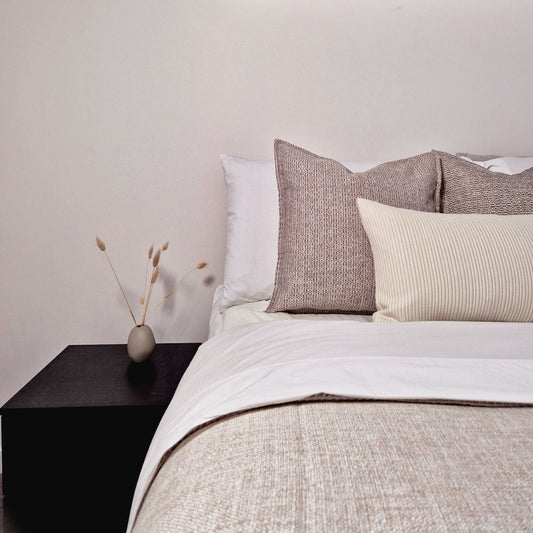 Ashen and dune cushion covers on a well made neutral bed
