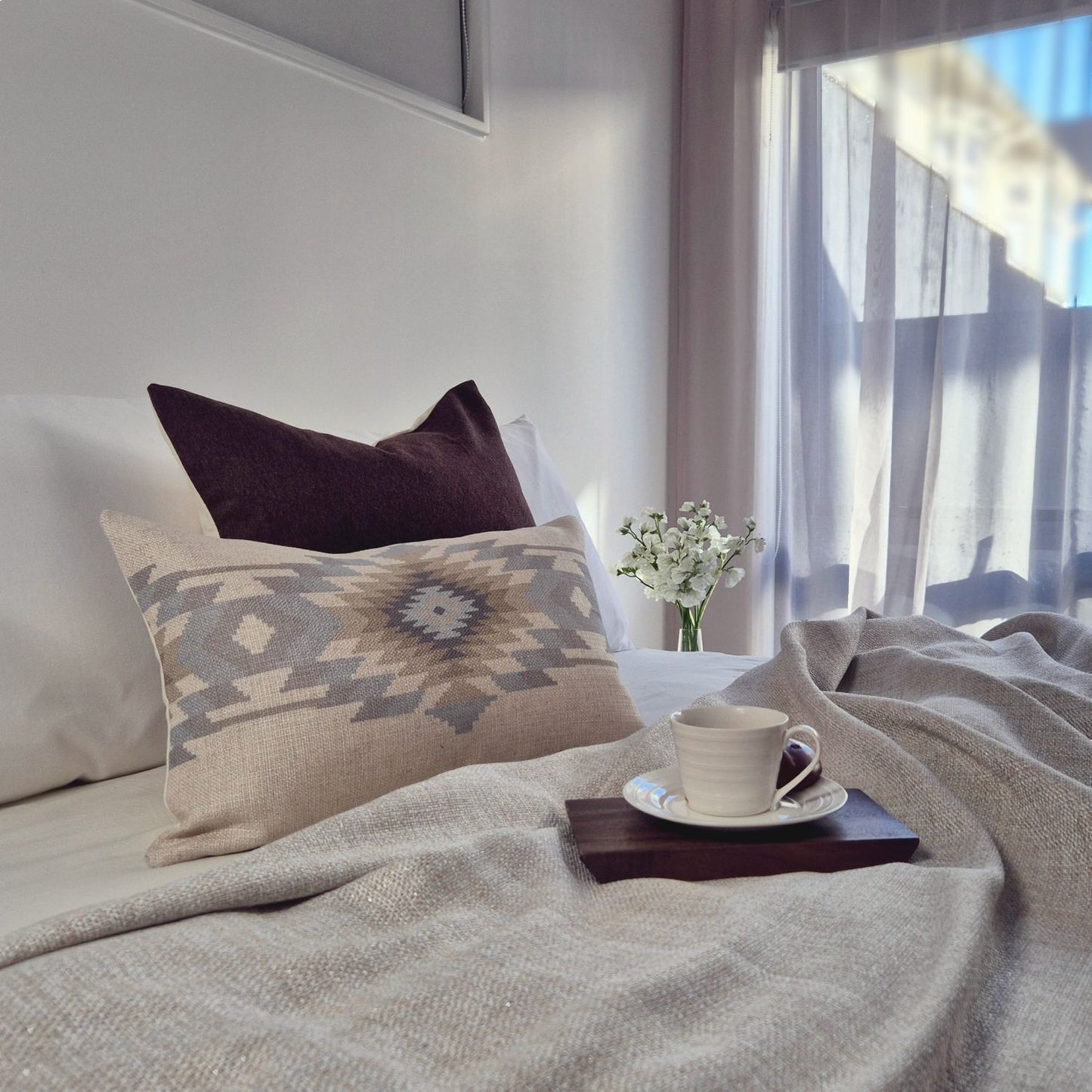 Decorative Threads cosy bedroom with cushions, a cup of coffee, and a vase of flowers on a tray.