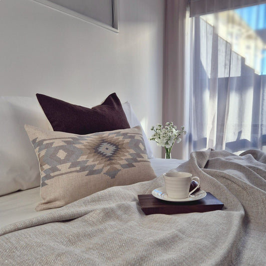 Decorative Threads cosy bedroom with cushions, a cup of coffee, and a vase of flowers on a tray.