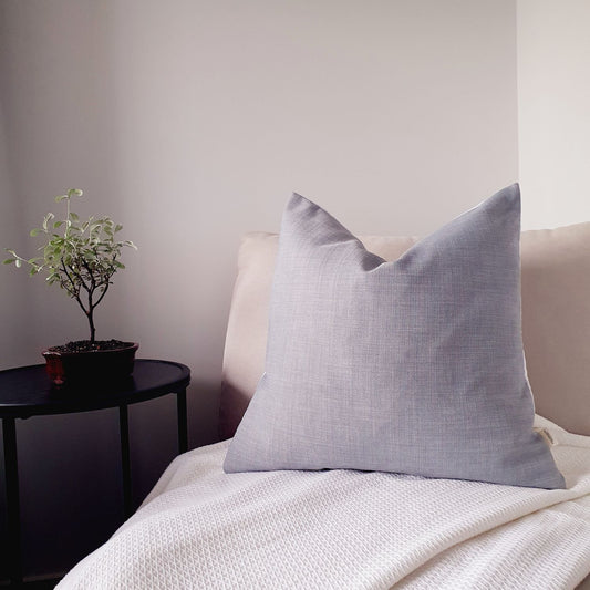Blue pillow on a sofa next to a small potted plant on a side table