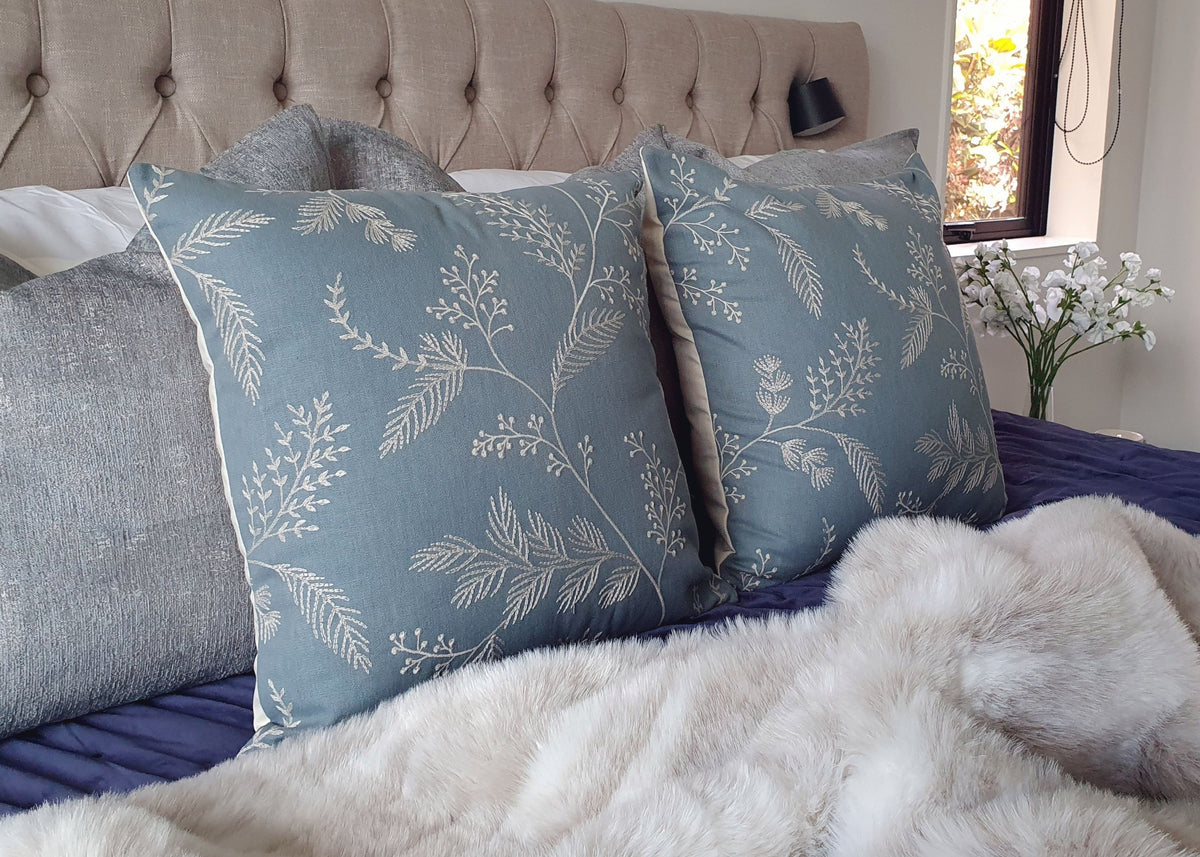 drift-medley-embroidered-cushions-by-decorative-threads-layered-on-a-bed