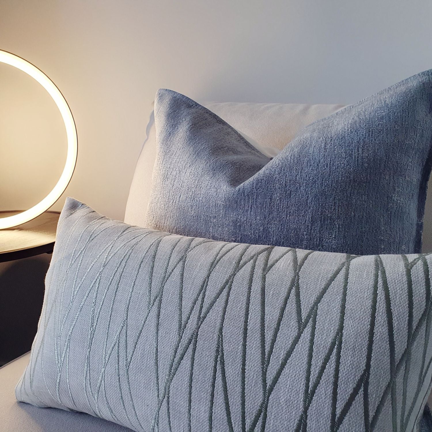 Decorative Threads Meadow cushion on a sofa with a modern light fixture in the background.