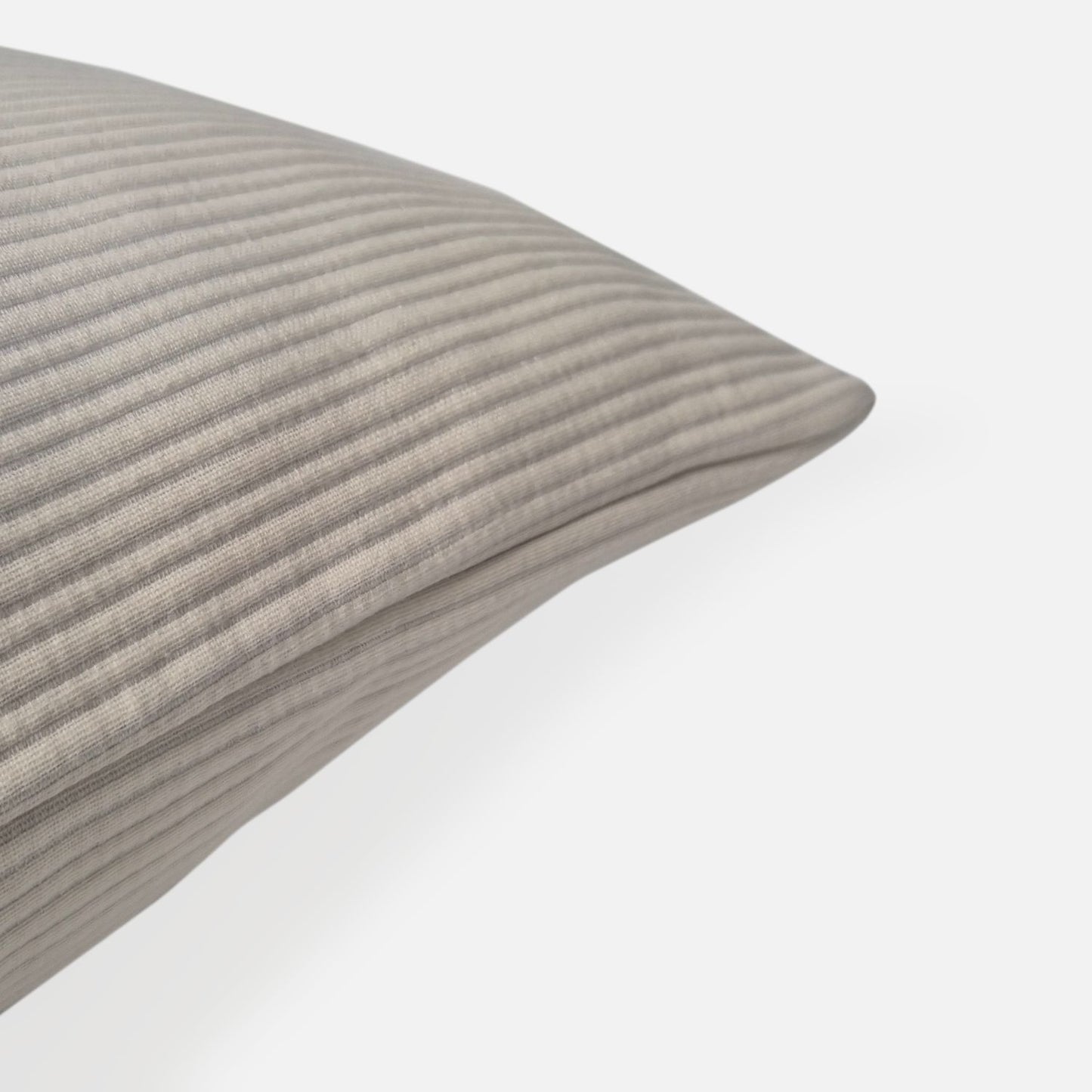 cream textured cushion with ribbed pattern, corner view on a white background