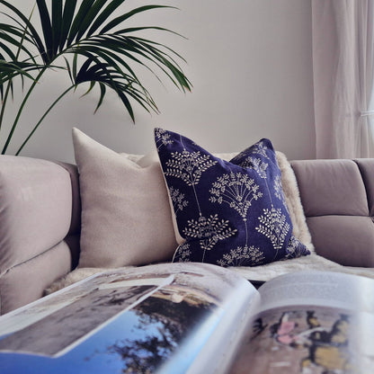 Decorative Threads Regal indigo cushion on a sofa with an open magazine and plant in the corner.
