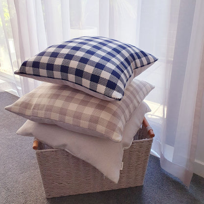 Sand and ink checkered cushions in a basket by a bedroom window