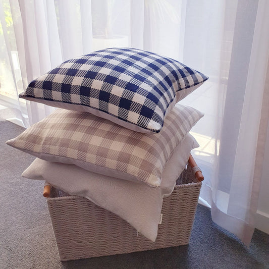Sand and ink checkered cushions in a basket by a bedroom window