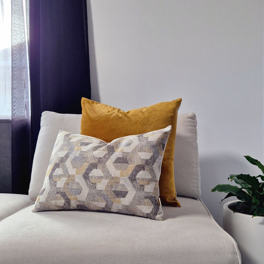 Decorative Threads Geometric Amber cushion cover combo on a cream sofa with plant. The duo features a rich honey coloured velvet paired with a contemporary geometric weave.