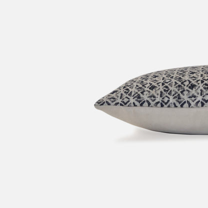 Close-up of geometric woven cushion cover featuring navy, cream and natural tones in a structured modern pattern.