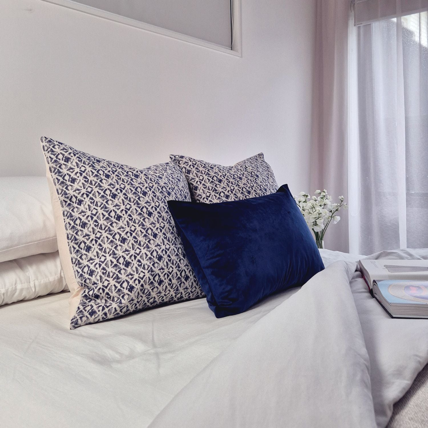 Luxury geometric cushion cover set of three styled on a neutral bed featuring modern woven textures and velvet detailing.