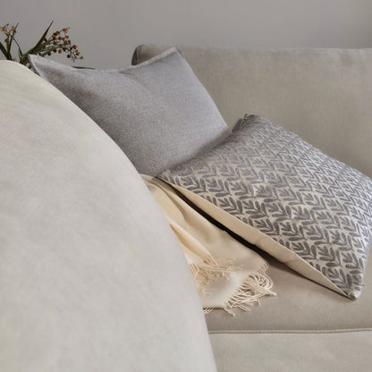 Decorative Threads Willow siliver and Hutt grey cushion covers with throw blanket on a beige sofa with a neutral background