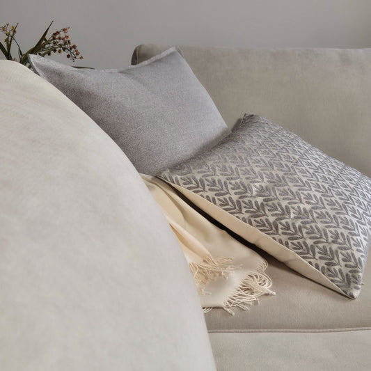 Decorative Threads Willow siliver and Hutt grey cushion covers with throw blanket on a beige sofa with a neutral background
