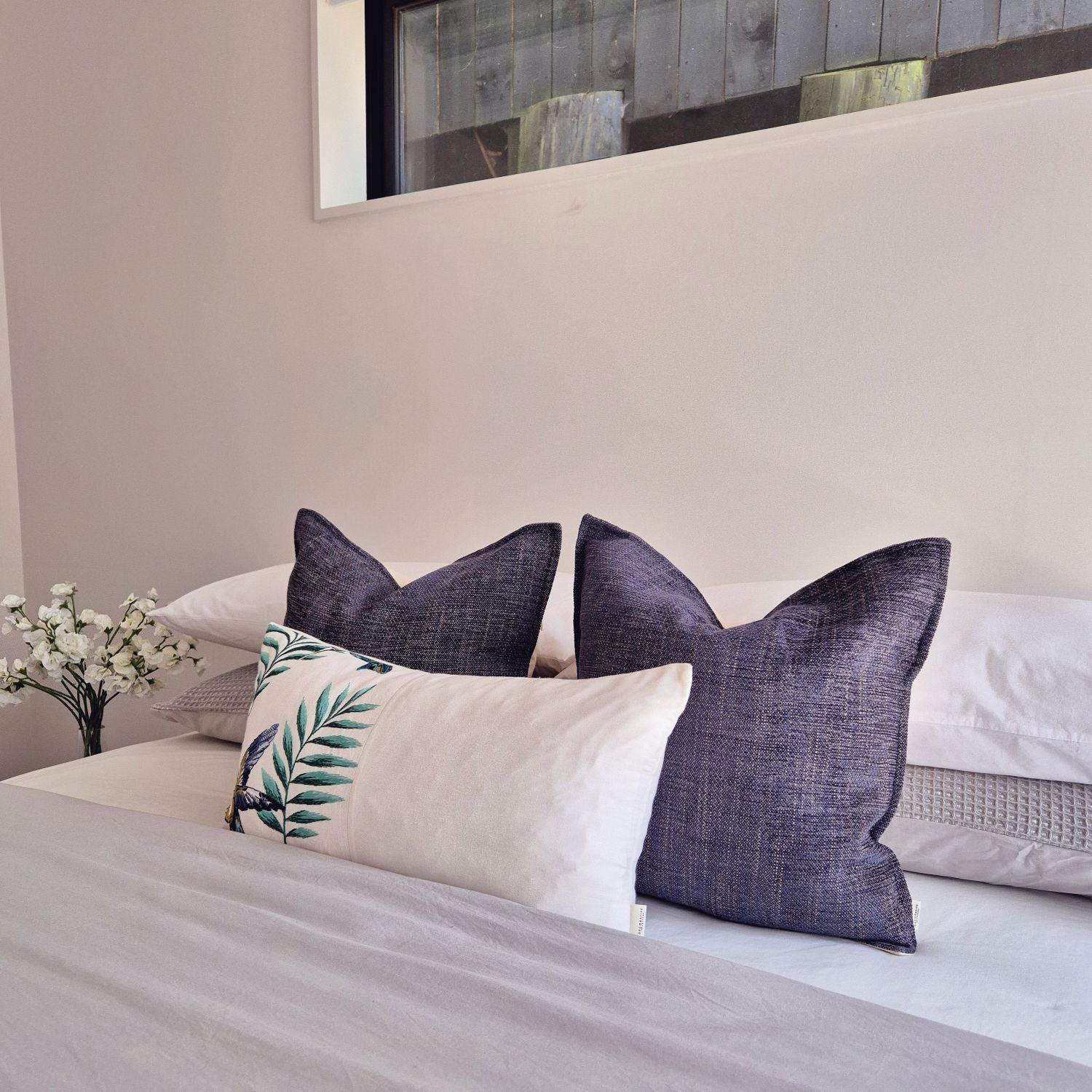 Avian Ivory embroidered botanical bird cushion paired with Twilight dark blue covers for a sophisticated, dreamy bedroom look by Decorative Threads.