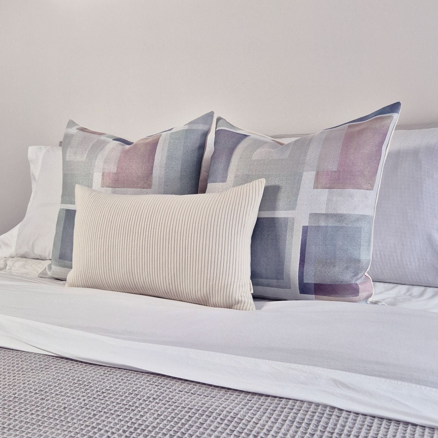 Decorative Threads Nebula cushion cover on a bed with a neutral colour palette