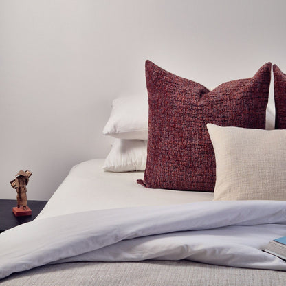 Decorative Threads Rustic Charm Cushion Combo in colour red and white on a bed with white bedding.