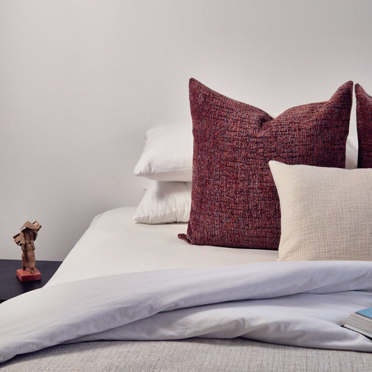 Decorative Threads Rustic Charm Cushion Combo in colour red and white on a bed with white bedding.