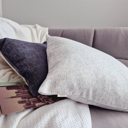 Decorative Threads textured rain cushion on a sofa with a book and blankdet