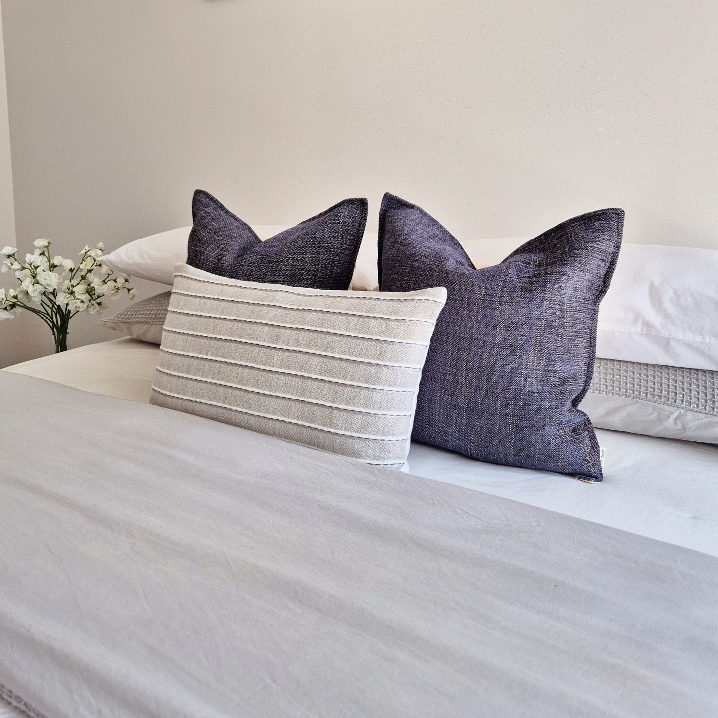 Decorative Threads twilight and ripple cushions neatly arranged on a bed with a neutral background