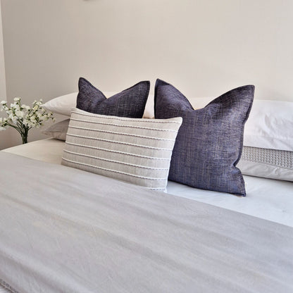 Decorative Threads twilight and ripple cushions neatly arranged on a bed with a neutral background