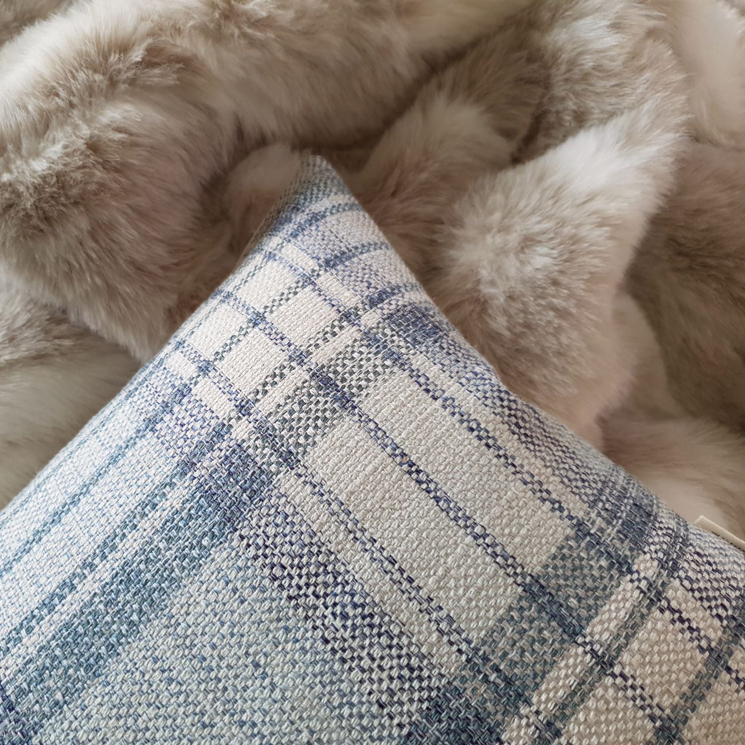 Light blue woven plaid cushion cover styled on a neutral sofa